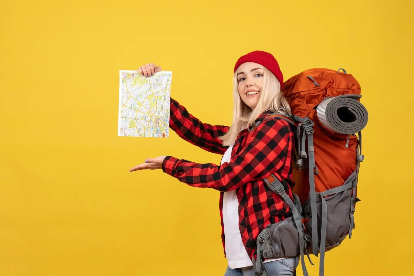 Frontalansicht eines blonden Mädchens mit ihrem Rucksack, das eine Karte hält.